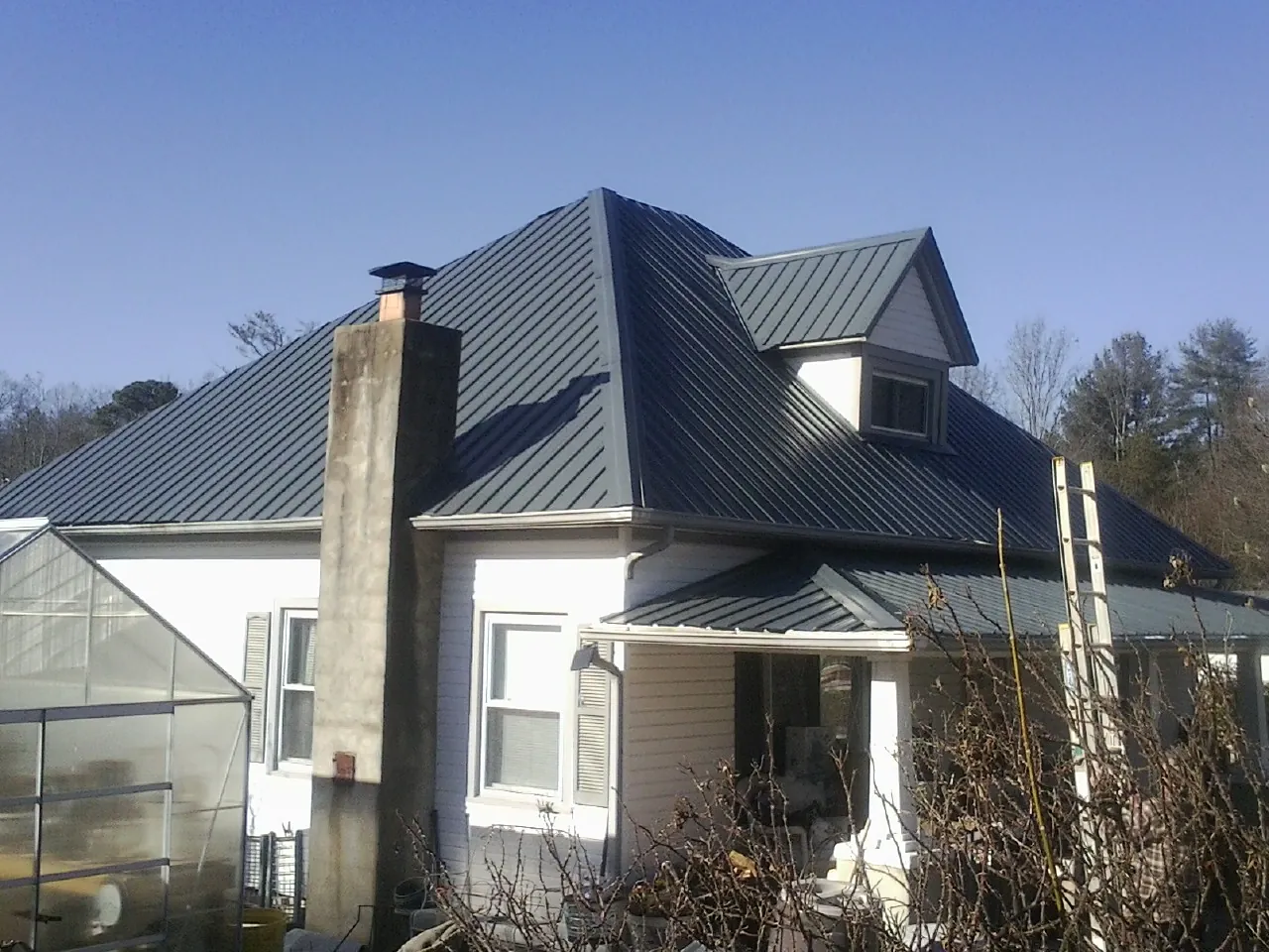 Dark blue standing seam metal roof on a white farmhouse with dormer — Slate & Tile Roof Repair by Roofing Brothers in Conestoga