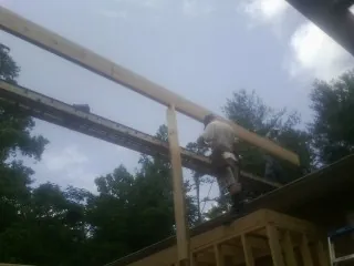 Carpenter setting a ridge beam over a new addition frame — Ice Dam Removal by Roofing Brothers in Conestoga