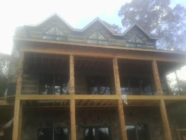 Dormers and porch framing on a large log home under construction — Roof Coating work by our crew in Conestoga