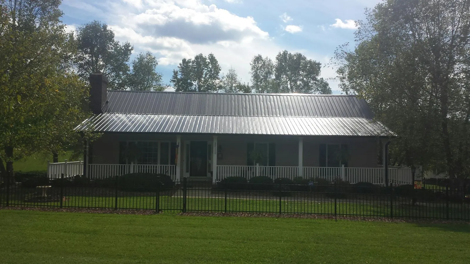 Gray metal roof on a brick ranch with a full width front porch — Gutter Guard Installation work by our crew in Conestoga