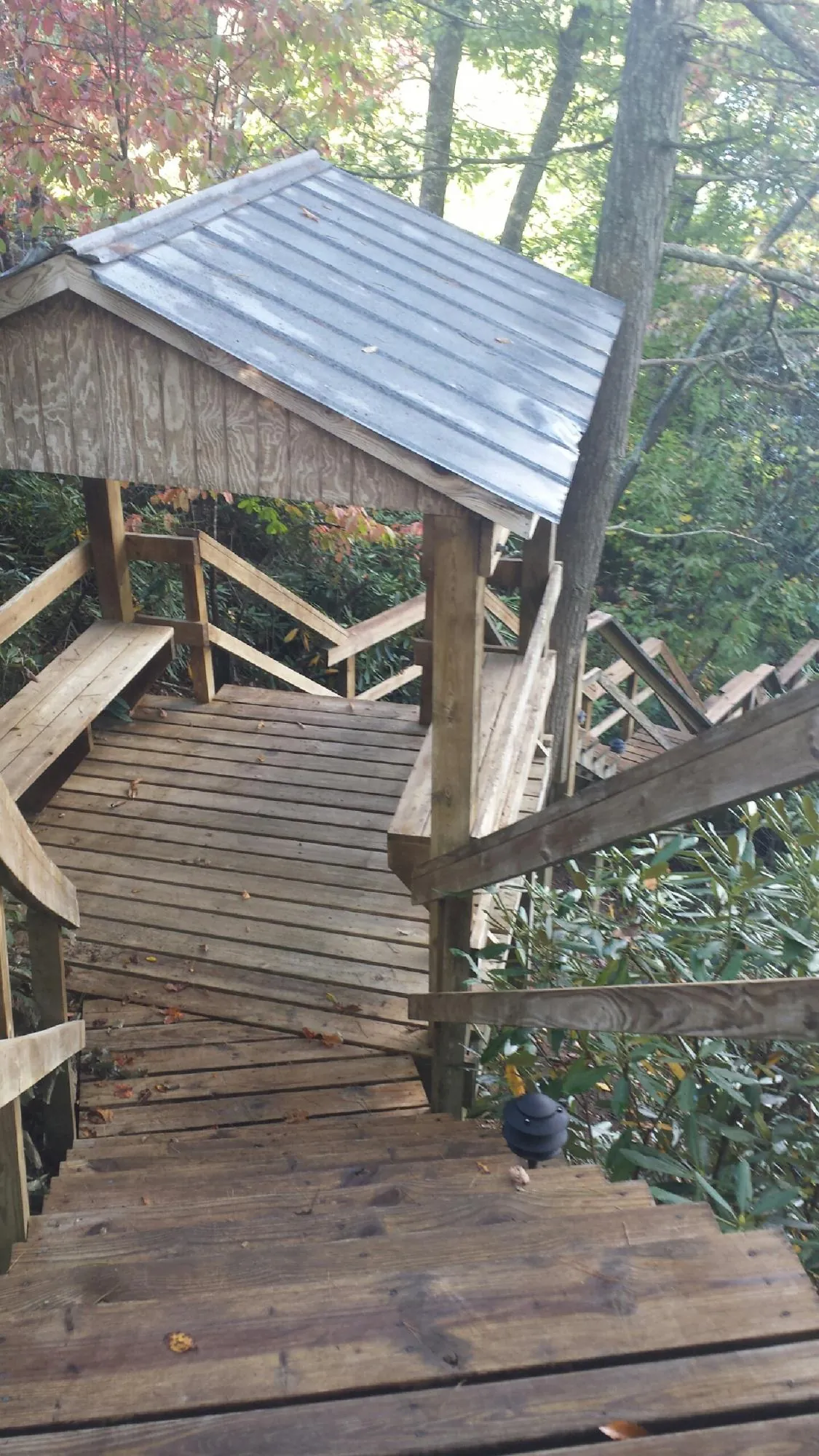 Metal roofed shelter over wooden steps on a wooded walkway — Skylight Repair & Installation work by our crew in Conestoga
