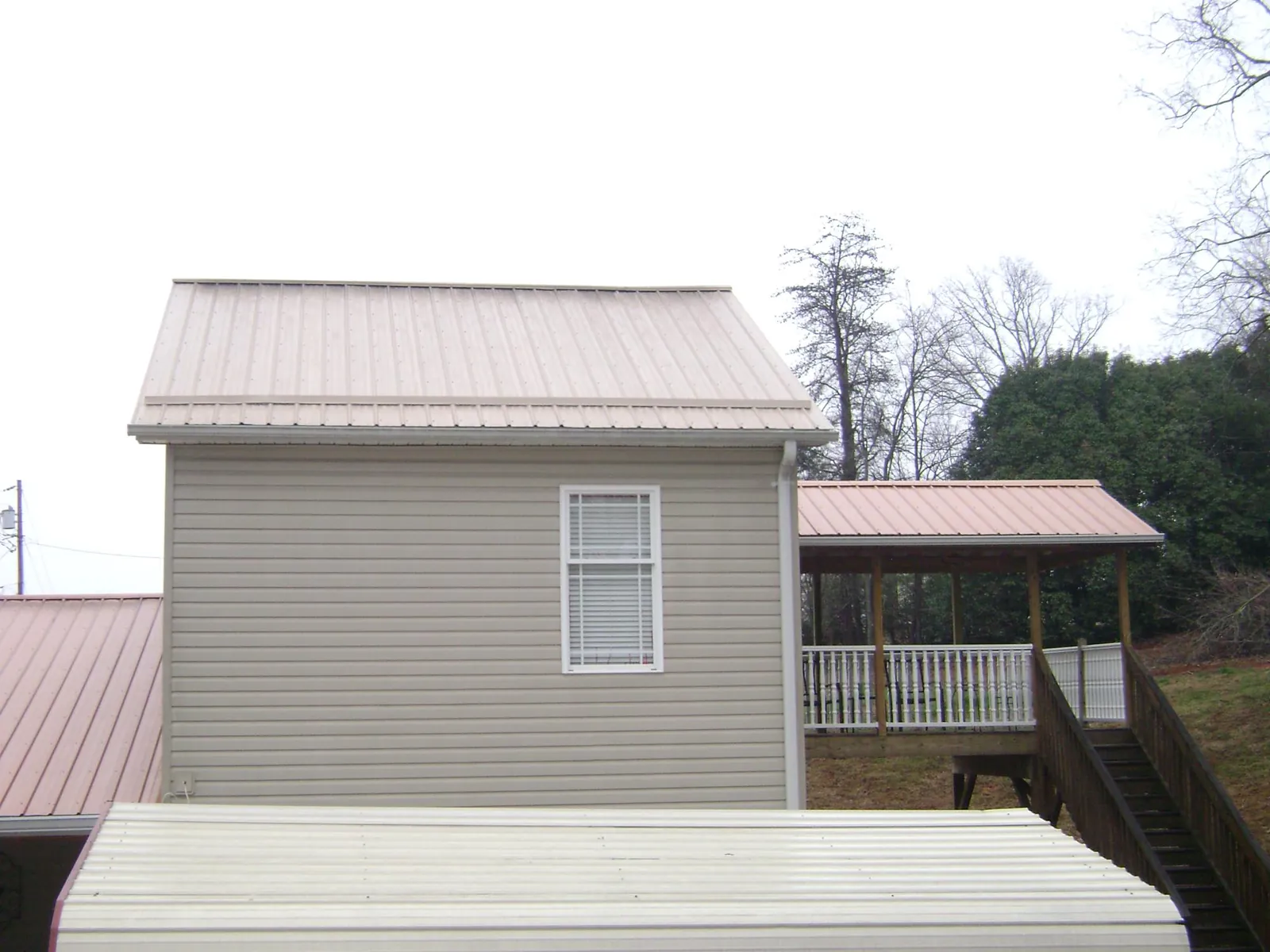 Tan metal roofs on a two story addition and attached porch, from a Roof Replacement job in Conestoga