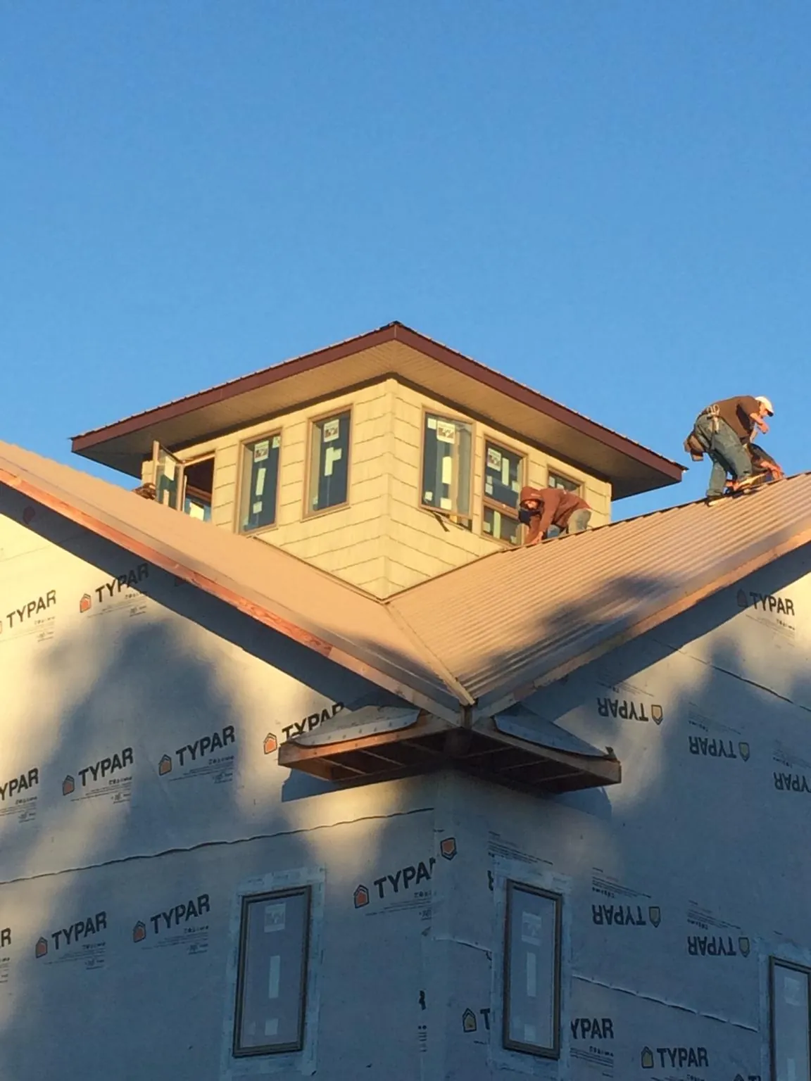 Roofers working around a rooftop cupola on a new metal roof at sunset — Roof Waterproofing in Conestoga by Roofing Brothers